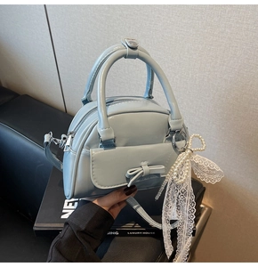 Detail of light blue patent leather bowling bag with pearl pendant and bow decoration