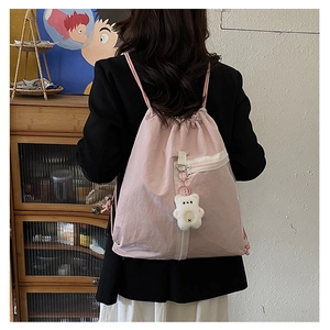 Detailed view of pink drawstring backpack with teddy bear charm and sleek zipper pocket