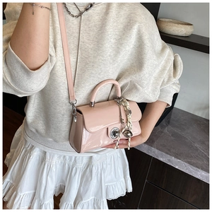Détail du mini sac en cuir verni rose clair avec fermoir argenté et breloque déco