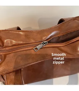 Detail of silver hardware zipper pull on brown leather tote bag with smooth texture