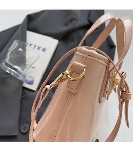 Detail of pink glossy patent leather handbag with premium golden metal hardware and lobster clasp