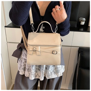 Detail van crème vintage handtas met strikaccent en zilveren hardware op een model