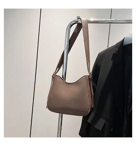 Détail de la texture cuir grainé marron foncé et boucle métallique sur le sac bandoulière