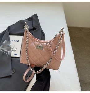 Detailed view of pink quilted crescent bag with silver chain strap on a blazer background