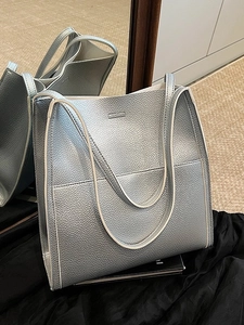 Minimalist silver tote bag with lychee texture and long shoulder strap in a mirror view