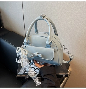 Detail of light blue bowling bag featuring a glossy patent finish and decorative lace bow