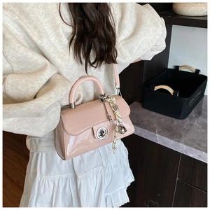 Détail sac bandoulière en cuir verni rose avec fermoir rotatif argenté et foulard fleuri