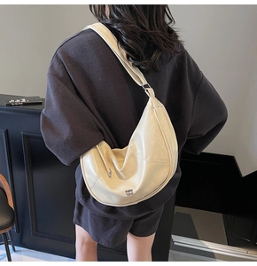 Détail du sac bandoulière croissant crème montrant le cuir souple et la bandoulière