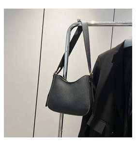 Détail du sac hobo en cuir grainé noir avec boucle dorée sur un support métallique