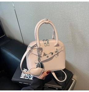 Close-up of light pink shell-shaped handbag featuring silver buckles and heart charm