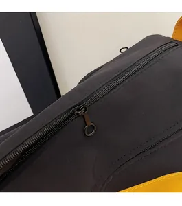 Détail de la fermeture éclair et du tissu en nylon de ce sac Boston noir et jaune