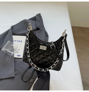 Detail of black quilted moon bag with silver chain and metal twist lock closure