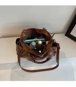 Spacious interior of a dark brown faux leather tote bag with various daily essentials