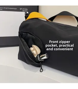 Détail de la poche zippée avant sur le sac Boston en toile noire avec poignées jaunes