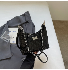 Detailed view of black quilted hobo bag with silver turn-lock and chain strap