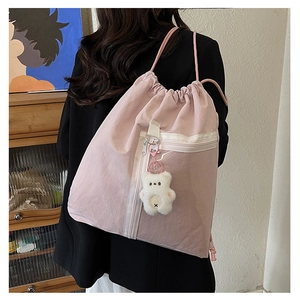 Detail of pink canvas drawstring backpack with cute plush bear pendant on model