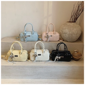 Detailed view of five colorful Boston handbags with bow charms on a stone background
