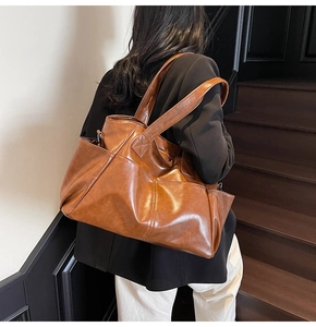 Brown faux leather tote bag with side pockets shown on model during a stylish commute