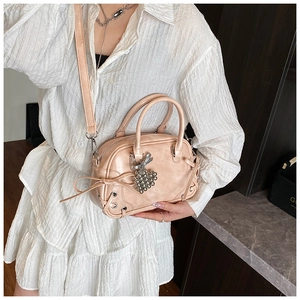 Détail d'un sac Boston rose avec breloque nœud argenté et bandoulière réglable