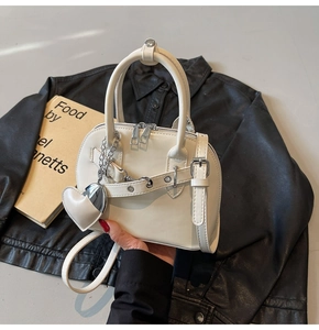 Close-up of white shell bowling bag featuring silver buckle belt and heart leather pendant