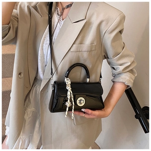 Détail d'un sac à main en cuir verni noir brillant avec fermoir argenté et foulard en soie