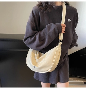 Détail du sac bandoulière beige en demi-lune avec large bandoulière et texture mate