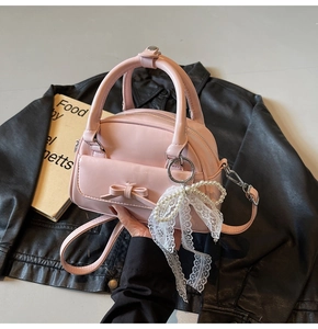 Detail of light pink mini bowling bag featuring a leather bow and elegant pearl charm