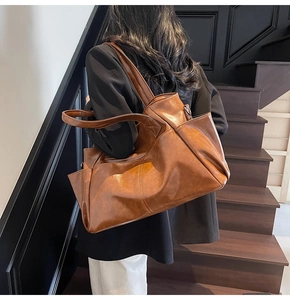Brown vintage faux leather tote bag with large capacity and side pocket shown on shoulder