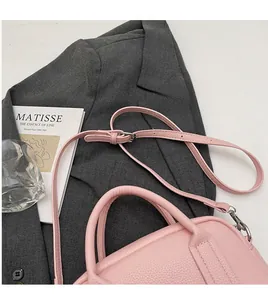 Detailed close-up of pink litchi grain leather mini bag with stitching and slim shoulder strap