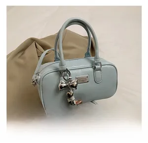 Detail view of baby blue Boston bag with silver bow charm and textured leather