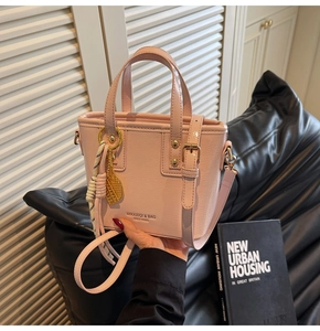 Close-up of pink bucket bag featuring golden tennis racket charm and brand lettering