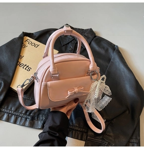 Pink patent leather bowling bag with delicate pearl lace pendant on a black jacket
