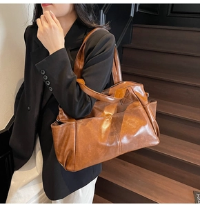 Detail of a large brown retro PU leather tote bag worn as a shoulder bag on a model