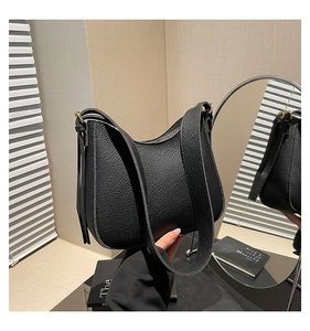 Détail d'un sac bandoulière en cuir noir grainé avec ferrures dorées et bandoulière large