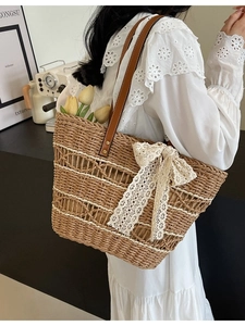 Summer straw tote bag with brown leather straps and beige lace bow on white dress model