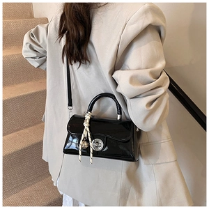 Détail d'un sac bandoulière en cuir verni noir avec foulard et fermoir argenté