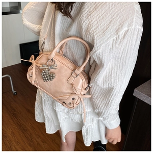 Sac Boston beige à nœuds avec breloque cœur porté à l'épaule par un mannequin