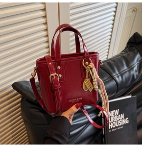 Detail of red patent leather bucket bag featuring gold hardware and unique charms