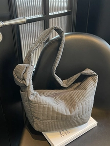 Chic grey quilted nylon crossbody bag with knotted strap detail on a chair