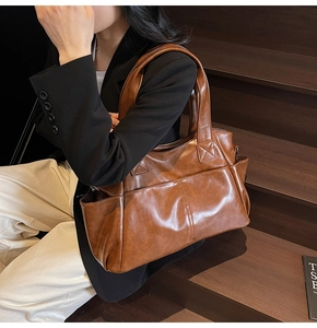 Detail shot of a large brown vintage tote bag with functional pockets and polished texture