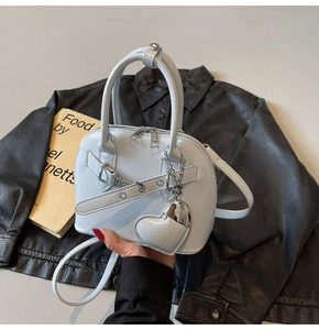 Close-up of light blue shell bag with silver heart charm and smooth leather texture