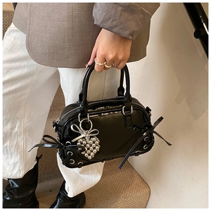 Détails du sac Boston noir brillant avec nœuds en ruban et pendentif cœur en métal
