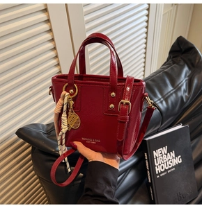 Close-up of red patent leather bucket bag with brand logo and creative tennis charm