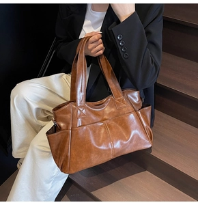 Close-up of brown faux leather tote bag with decorative X-stitch on wide shoulder straps