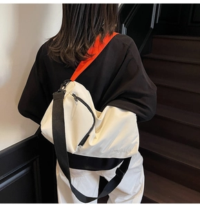Détail du sac Boston blanc montrant la large bandoulière réglable orange et noire