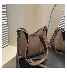 Gros plan d'un sac hobo en cuir litchi marron foncé avec boucles dorées et bandoulière