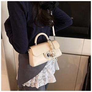 Détail du sac à bandoulière en cuir verni beige avec foulard et boucle en métal