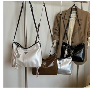Detail of four versatile shoulder bags in white, brown, silver and black with metal logo
