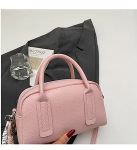 Detailed macro shot of pink lychee grain leather texture on a mini Boston handbag