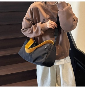 Détail du sac Boston noir en toile avec intérieur et bandoulière jaunes contrastés